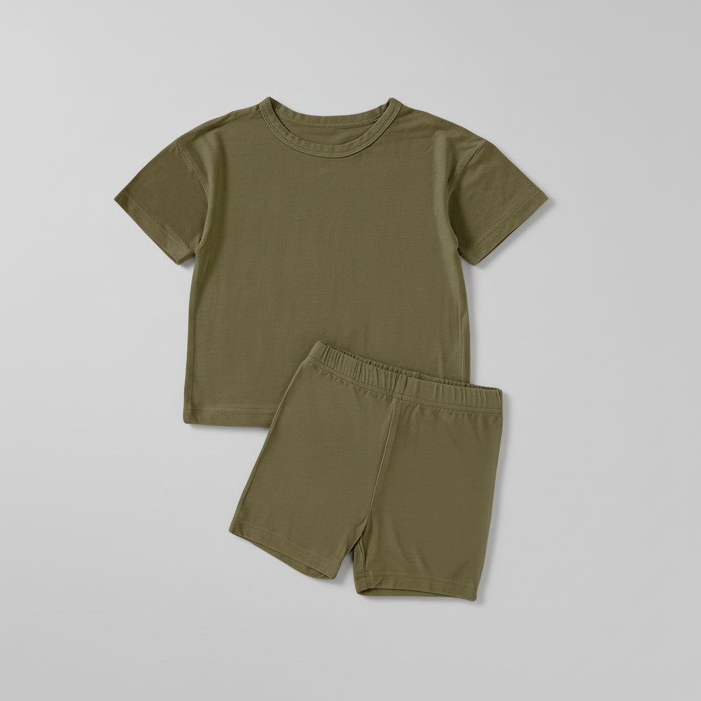 Children's green t-shirt and shorts set with brown shoes on a beige background
